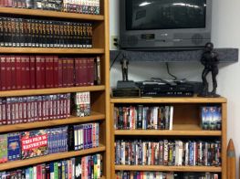 Library media corner containing DVDs, CDs, and VHS tapes.